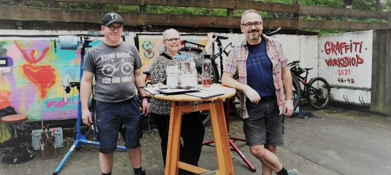 Drei Männer stehend an einem Tisch