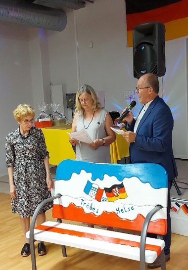 Kunstbank wird überreicht Drei Personen und eine bunte Bank