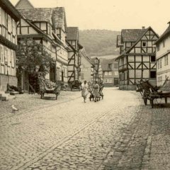 Straße in 30`gern, Frauen die die Straße entlang gehen, ein Huhn am Straßenrand ,schwarz/weißes Bild