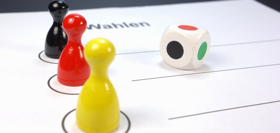 Bundestagswahl, Spielfiguren in Nationalfarben und ein Spielwürfel 